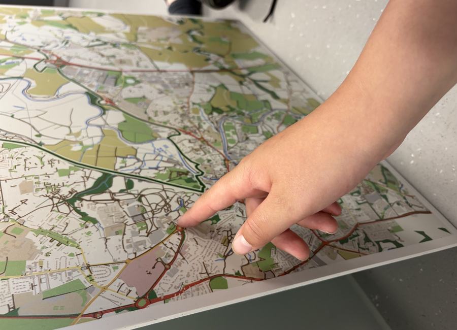 A hand pointing to a local map during a place-based activity.
